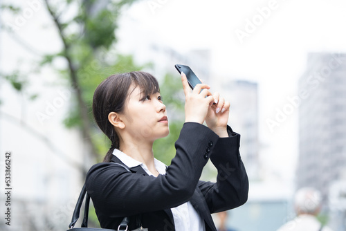 屋外でスマートフォンを使うスーツ姿の若い女性