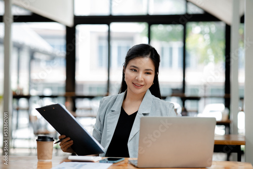 Asian woman working on laptop, female employee of a marketing company, she is working on a marketing plan for a company to generate income and profit, grow sales. Marketing planning concept.