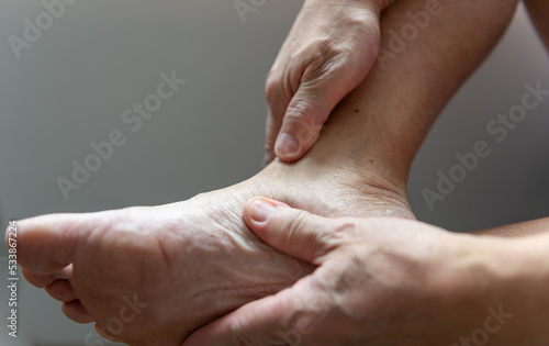 A person massaging foot ankle joint suffering from arthritis.