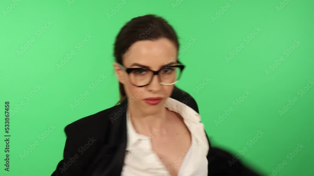 Businesswoman with glasses and ponytail wearing white shirt and black business attire uses boxing gloves to punch toward camera. Green screen for chroma key in background Businesswoman with glasses and ponytail wearing white shirt and black business attire uses boxing gloves to punch toward camera. Green screen for chroma key in background