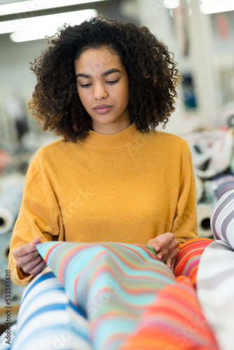 young woman looking at stripe colored fabric photo