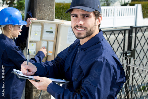 electrician workers inspecting electric meter outdoors