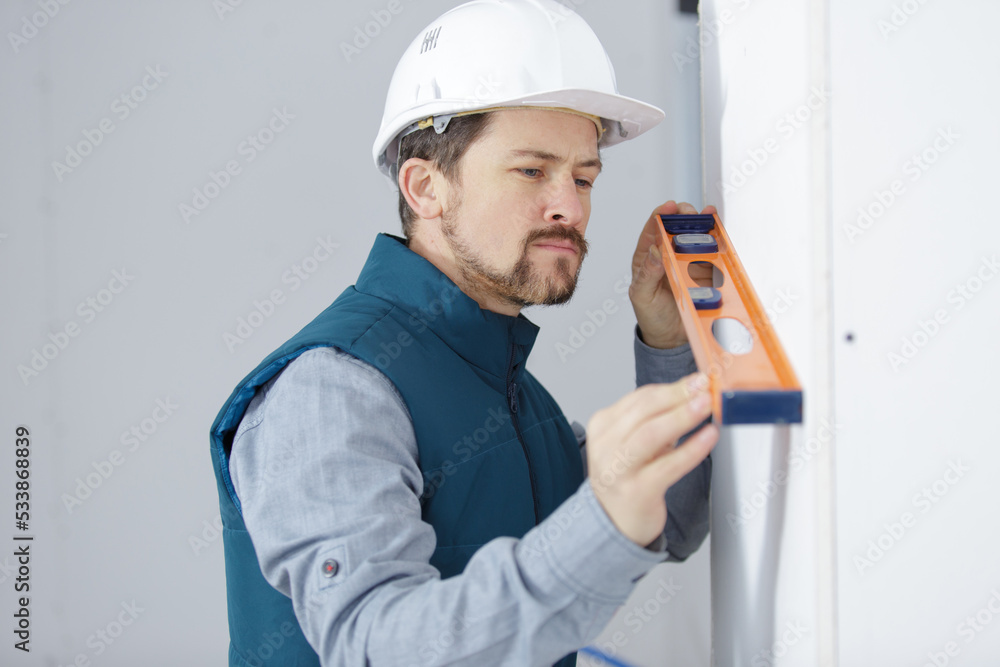 young homeowner using a spirit level on a wall young homeowner using a spirit level on a wall