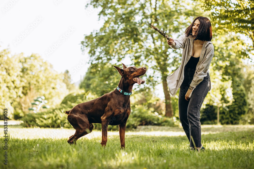 Woman with her dog doberman having fun in park Woman with her dog doberman having fun in park