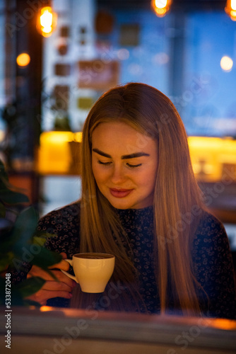 beautiful blonde woman with long hair drinking coffee in cafe
