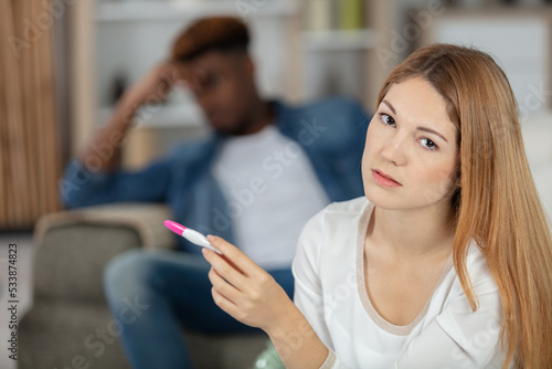 pcture showing sad woman with pregnancy test in bedroom photo