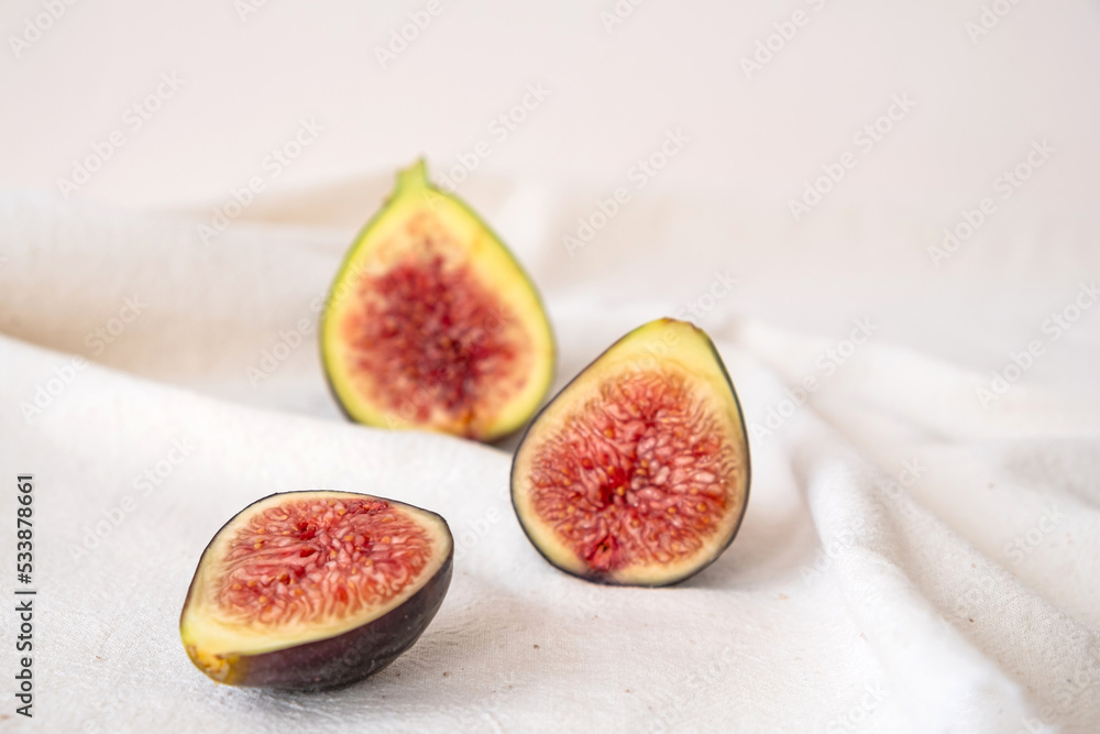 Fresh ripe and sweet figs halved on beige color table cloth.