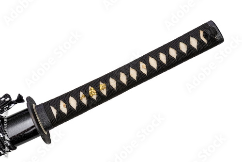 Close up shot of Tsuka - handle of Japanese sword wrapped by black silk cord on white ray skin with a small piece of gold decoration called Menuki isolated in white background. Selective focus. photo