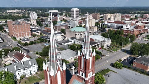 Aerial fly through steeples of historic St. Joseph Catholic Church in downtown Macon, Georgia revealing views of auditorium,  hotel, and courthouse. Filmed late afternoon in September 2022. photo
