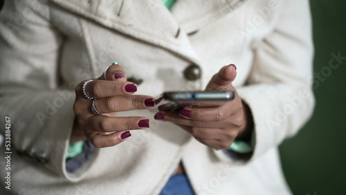 Closeup of a black woman hands holding cellphone device scrolling screen. African American person holding phone touching screen