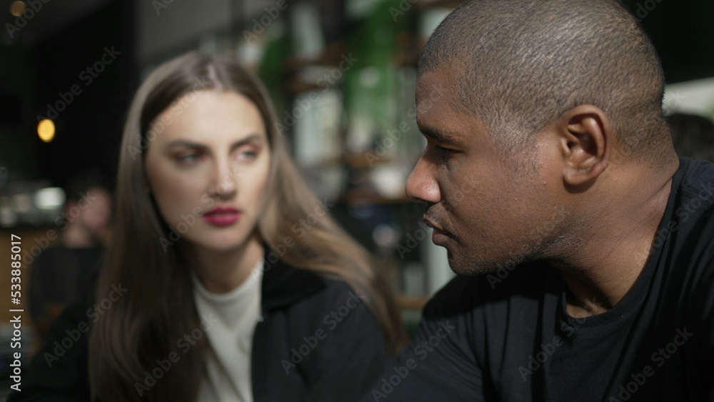 An interracial couple seated at coffee shop talking. Candid people at cafe restaurant in conversation. two people. diversity concept An interracial couple seated at coffee shop talking. Candid people at cafe restaurant in conversation. two people. diversity concept