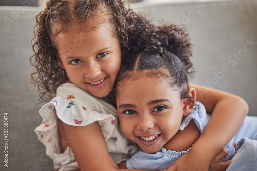 Photography Happy, smile and portrait of sisters hugging while sitting on a sofa in the living room at the family home