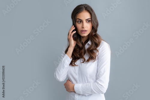 Girl talking on phone. Serious business woman with smartphone, chat, sms concept. Isolated over gray background. Mobile offer. Girl chatting by mobile phone.