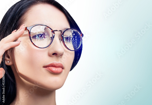 Woman with eye chart reflected in glasses. Optometry concept. photo