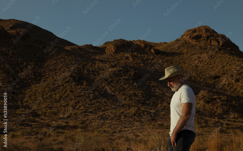 Side view of adult man in cowboy hat against mountain and sky Side view of adult man in cowboy hat against mountain and sky