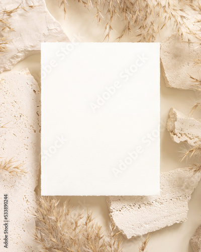 Blank card near beige travertine stones and dried pampas grass top view, greeting mockup © katrinshine