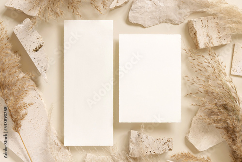 Blank cards near beige travertine stones and dried pampas grass top view, greeting mockup © katrinshine