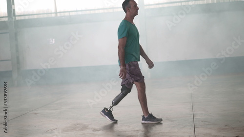 A disabled middle aged man walking with his prosthetic leg indoors