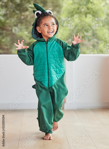 Child, smile and excited in halloween dinosaur costume at home playing role and having fun at party. Happy kid being playful with fantasy character in living room mimic animal actions ready to roar.