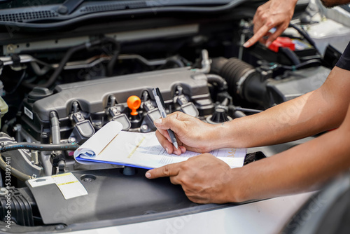Closeup and crop auto repair post a list of repairs according to customer orders on car engine background.