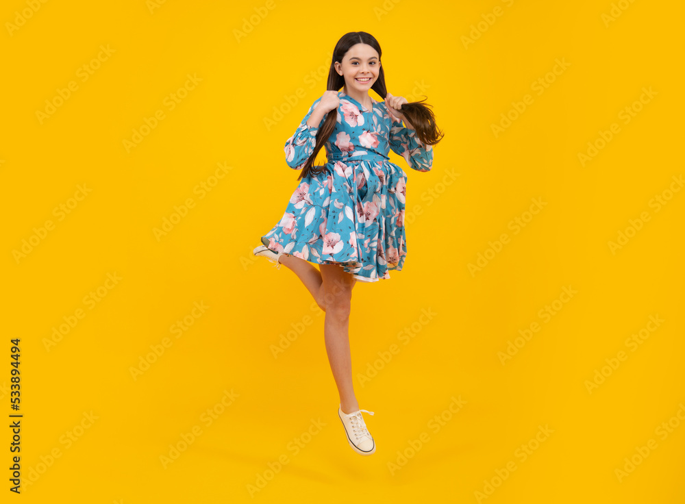 Happiness, freedom, motion and child. Young teenager girl jumping over yellow background, funny jump. Excited face. Amazed expression, cheerful and glad.