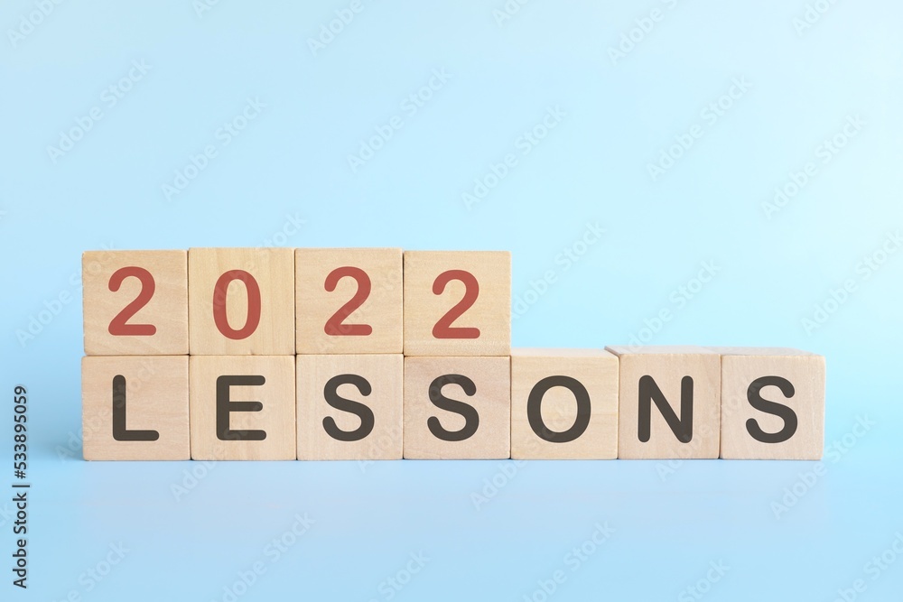 Year 2022 life lessons and learnings concept. Wooden blocks in blue background. Year 2022 life lessons and learnings concept. Wooden blocks in blue background.
