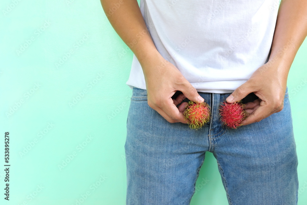 Male testicle health and nutrition, itchy, red, hairy and swollen balls  concept. Young asian man holding two red fruits on crotch area. Stock Photo  | Adobe Stock