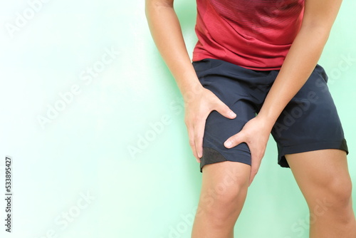 Leg pain and injury concept. Young asian athlete man in running clothes holding his thigh muscle with copy space.