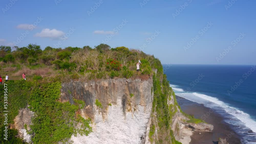 Aerial dolly out revealing young father lifting his infant son up a cliff on a tropical beach in Bali like in the lion king Aerial dolly out revealing young father lifting his infant son up a cliff on a tropical beach in Bali like in the lion king