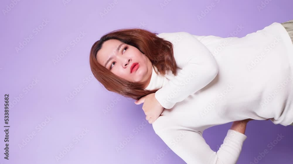 Vertical of Sick tired woman suffering intense neck and shoulder pain touching sore stiff muscles and frowning from ache feeling overworked isolated over a violet background Vertical of Sick tired woman suffering intense neck and shoulder pain touching sore stiff muscles and frowning from ache feeling overworked isolated over a violet background