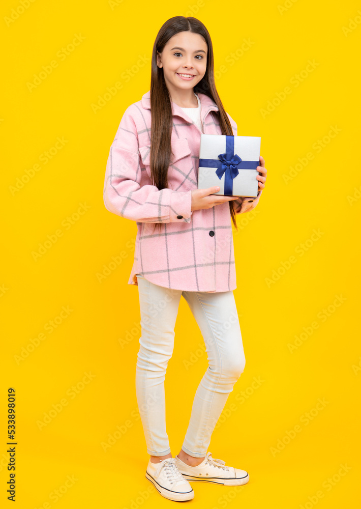 Fototapeta premium Teenager child with gift box, studio isolated background. Present for birthday, Valentines day, New Year or Christmas. Kid hold present box with gift ribbon bow.