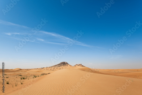 Sand Dunes landscape with Mountains in the background and with blue sky with large copy space