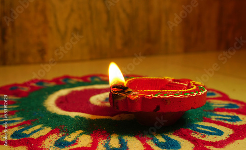 Oil lamps (Clay diya) lit on colorful rangoli during diwali celebration.Greeting Card Design Indian Hindu Light Festival called Diwali.