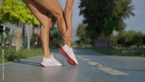 Young sportswoman having pain or injury during exercise and jogging on running track