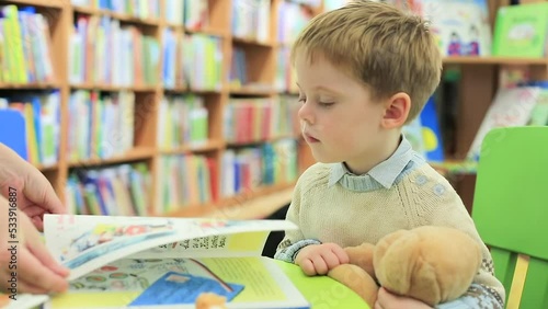 A mother shows her son a children's picture book. Mother and son in the library