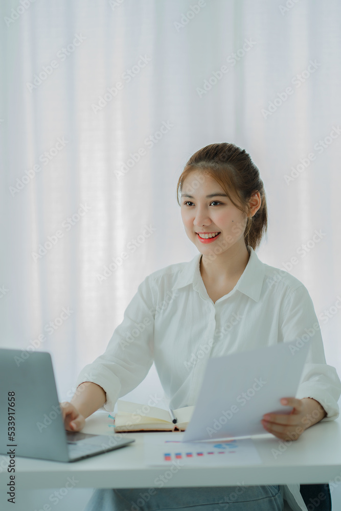 Beautiful Asian woman smiling happily relaxing using laptop computer in office. creative young girl working and typing on keyboard online work concept vertical picture Beautiful Asian woman smiling happily relaxing using laptop computer in office. creative young girl working and typing on keyboard online work concept vertical picture