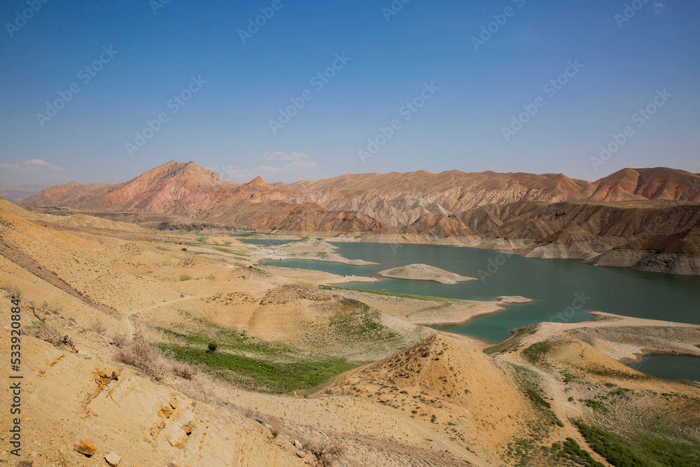 View of a mountain valley with a Azat river reservoir with a bright turquoise color in Armenia and arid terrain in the background.