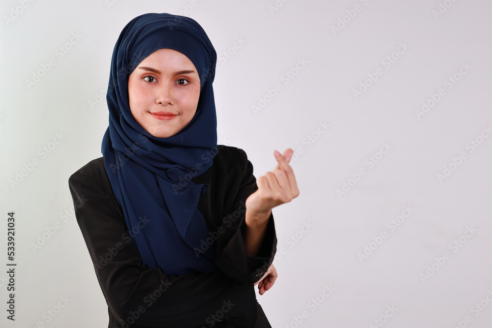 Happy smart asian business woman in muslim dress standing while doing mini heart symbol and looking at camera with confident in studio. Isolated white background portrait with beautiful face in hijab. Happy smart asian business woman in muslim dress standing while doing mini heart symbol and looking at camera with confident in studio. Isolated white background portrait with beautiful face in hijab.