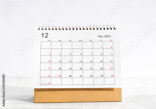 december 2023 Desktop calendar for planners and reminders on a wooden table on a white background.