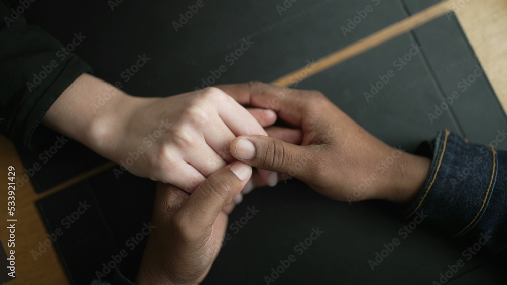 Young diverse couple hands closeup joining together in union. Romantic people holding hands in affection