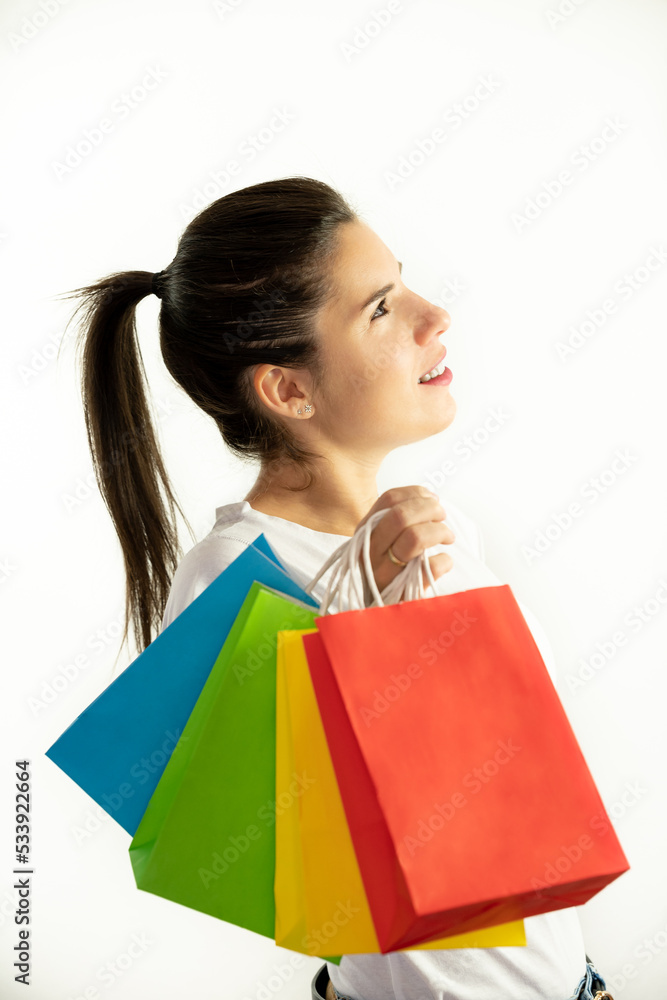 Woman in profile holding colorful bags on a white background - shopping concept, sales, black friday, christmas Woman in profile holding colorful bags on a white background - shopping concept, sales, black friday, christmas