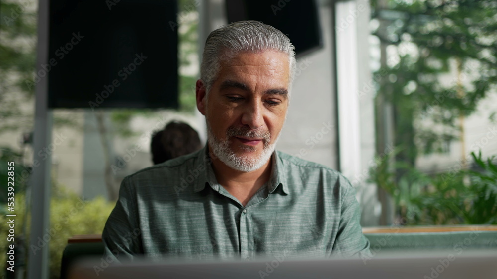 Thoughtful older businessman seated at coffee shop in contemplation. Pensive senior executive thinking about business looking out window Thoughtful older businessman seated at coffee shop in contemplation. Pensive senior executive thinking about business looking out window
