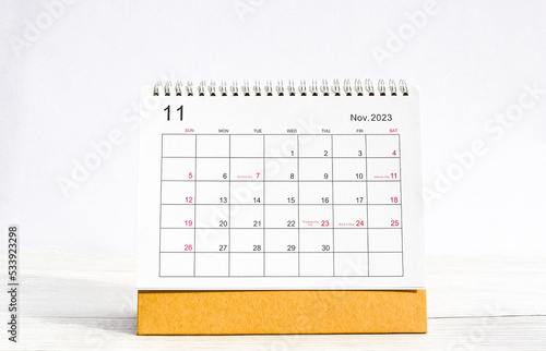 november 2023 Desktop calendar for planners and reminders on a wooden table on a white background.