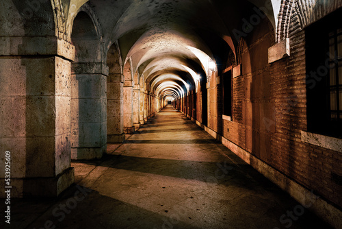 Billede på lærred A dusky colonnade leads the eye into a dark archway of perspective