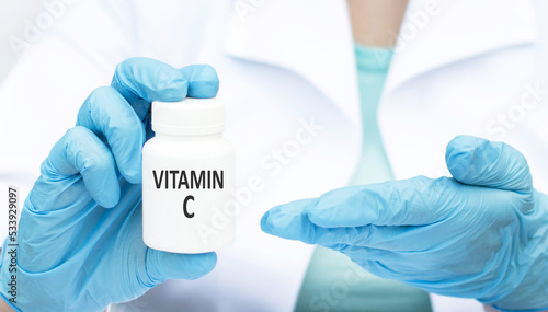 The doctor holds a jar with the text Vitamin C, Medical concept