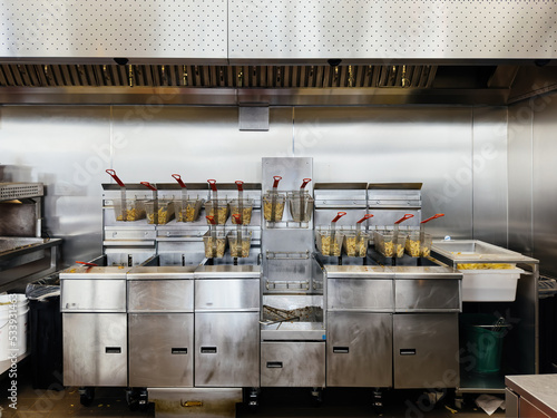 french fries cooking in multiple deep fryer mat machines inside fast food restaurant chain