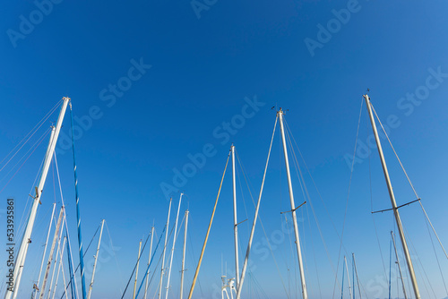 boat's sloops and masts with many ropes against a clear blue sky