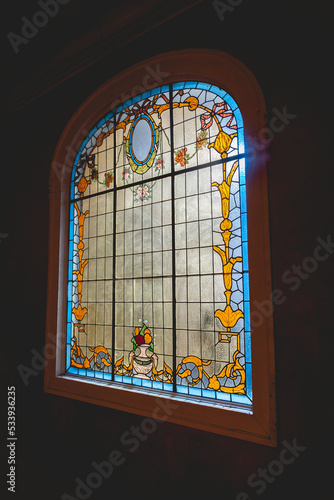 Big window with colorful antique stained glass with flowers and decorations, and back light