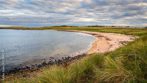 Football Hole Bay south of Snook Point  on the Northumberland coast  a designated Area of Outstanding Natural Beauty  known for its wide beaches high sand dunes punctuated by dark whinstone outcrops