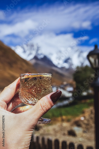 Georgian chacha alcohol, in a glass held by a woman, in the mountains of Georgia.
 photo
